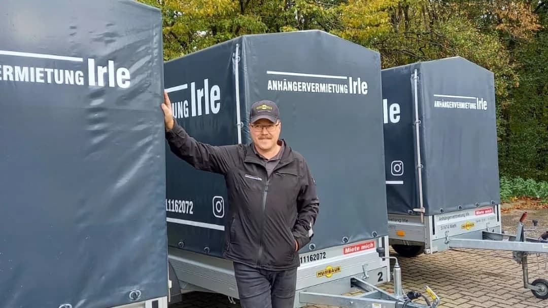 Detlef Irle steht zwischen seinen Planenanhängern
